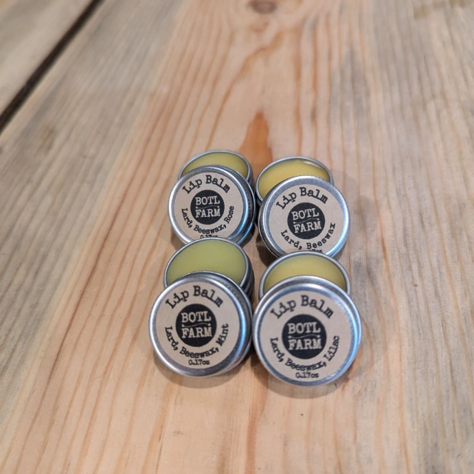 four metal tins of lip balm on a woodboard